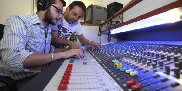 Due ragazzi alle prese con un tavolo di mixaggio musicale